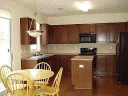 Cherry cabinetry, pantry, island, tile backsplash and hardwood floors