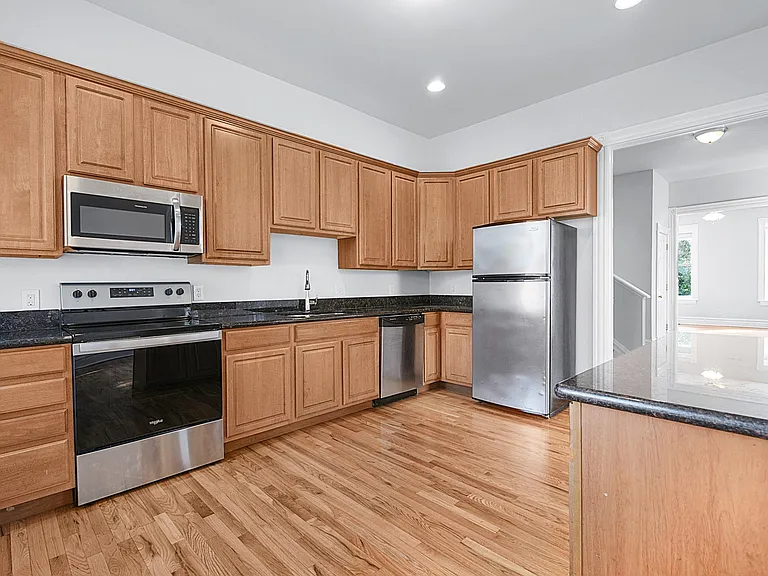 The Kitchen - granite countertops, luxury stainless steel appliance package, kitchen island great for eating or entertaining, looking towards The Foyer and The Living Room beyond.