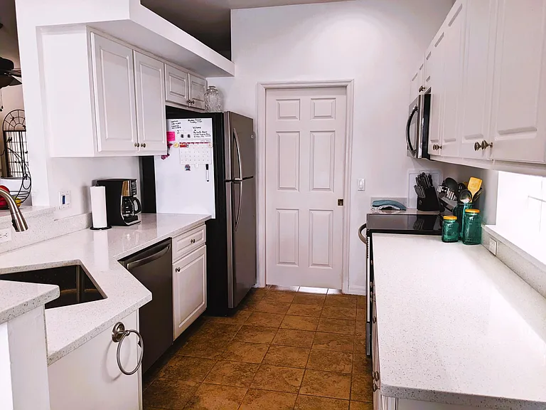 Kitchen with door to garage- all new appliances as of May 2022
New quartz countertops & white cabinets - large open sink, tile floor
Kitchen open to living/dining room.
Fully stocked with dishes, new pots and pans, small applicances and glass ware.