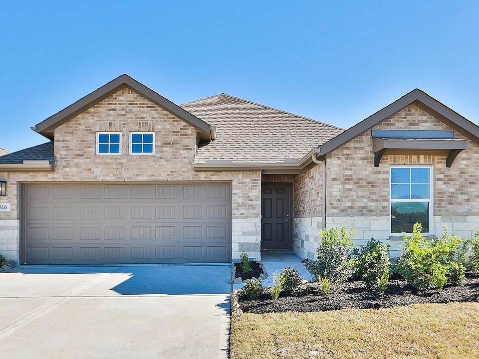 Embrace timeless elegance with this brick facade, steep gable roof, and meticulous landscaping at Ri