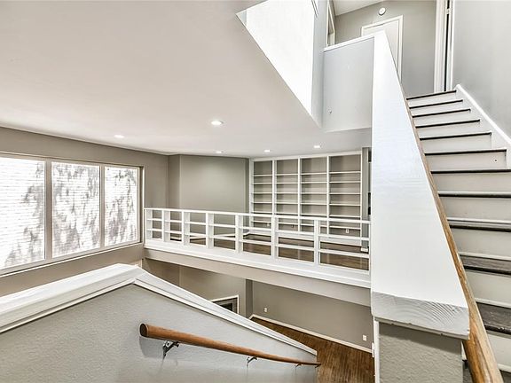 The dining room overlooks the main living area and doubled as a library with books on both the wall and railing. Large skylight on third floor lights up the staircase