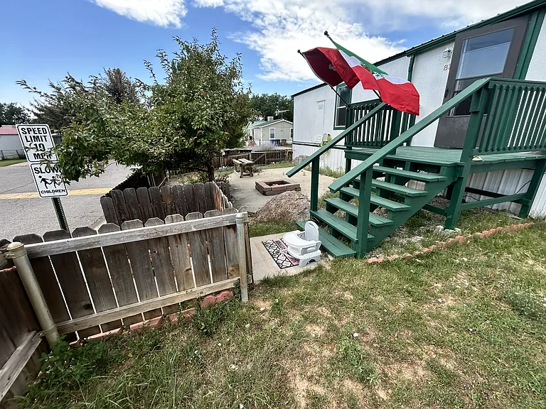 Front and back yard with sprinklers and small firewood pit on concrete slab