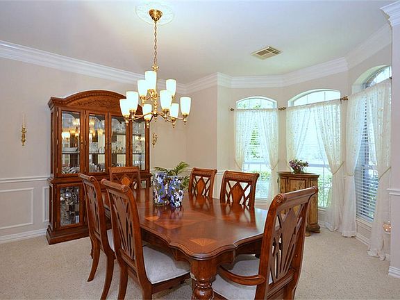 This formal dining room has a chandelier, a curved wall of windows allowing plenty of natural light 