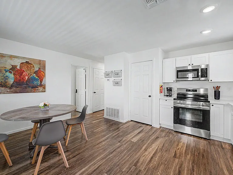 Open kitchen with white cabinetry, stainless steel range and microwave, plus a dining nook for everyday meals.