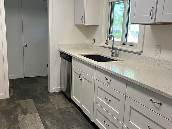 Updated kitchen with tile floors, granite countertops, stainless appliances, farm sink, and spacious pantry