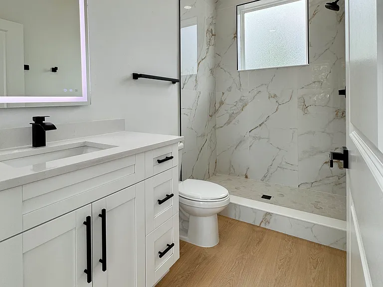 Sleek bathroom with walk-in shower and LED vanity mirror.