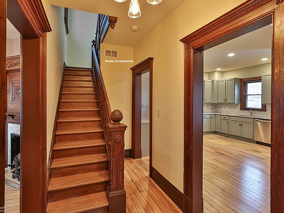 The photo showcases the entry area with the parlor, the staircase, and a view of the great room.