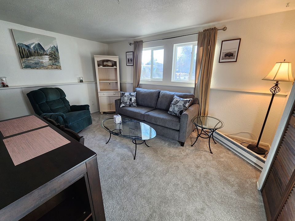 Apartment main living area with couch, end table, coffee table, bookcase, lazy boy, and kitchen table.