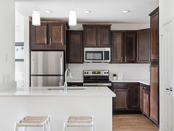 Gourmet kitchens feature quartz countertops, stainless-steel appliances, wood cabinetry, and modern designer details