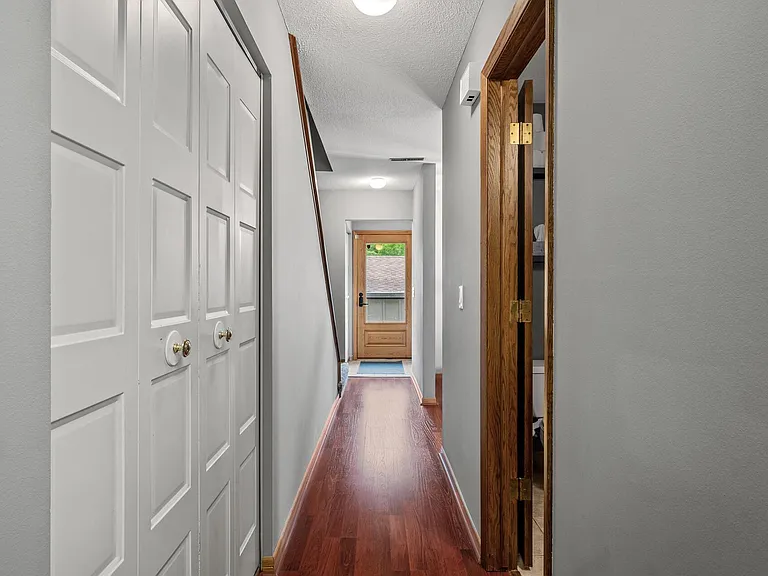 Looking down hallway to front door. Half bathroom on right. Left storage closet.