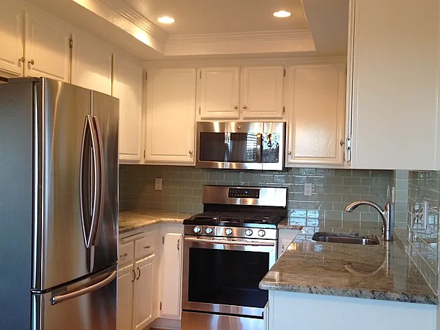 Stainless steel appliances, granite counters and glass backsplash