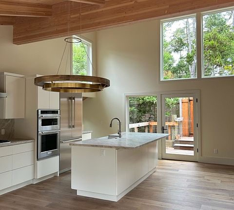Kitchen with island and wood beam ceilings opening into the great room