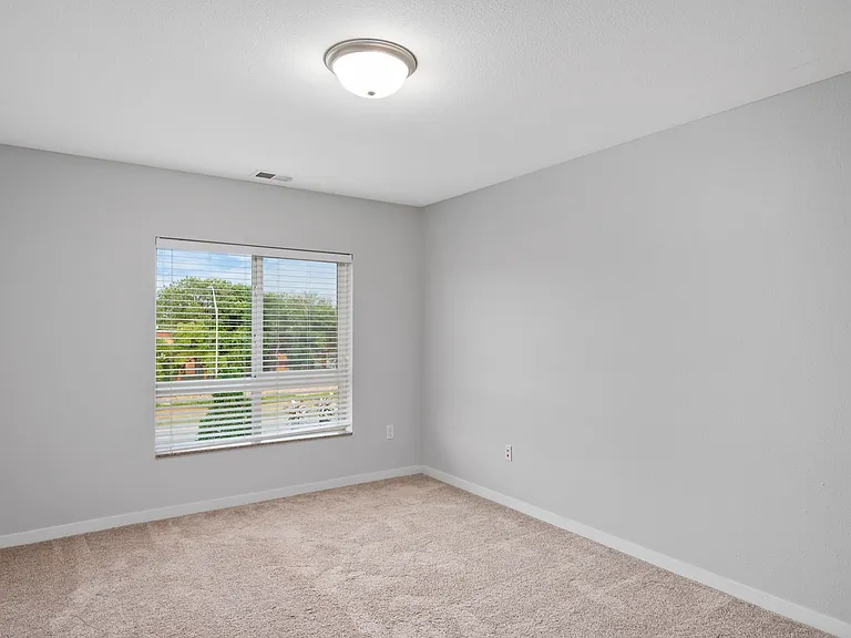 Bright and airy room with neutral walls and soft carpet, featuring a large window with serene outside view. Bright and airy room with neutral walls and soft carpet, featuring a large window with serene outside view.
