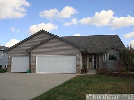 3 car garage with brick facade and wide driveway