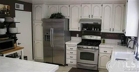 Stone flooring with beautiful cabinets, stainless steel appliances, and extra shelving for plates etc..