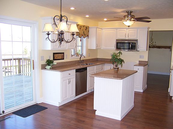 White kitchen cabinets with  beadboard detail and solid surface countertops
