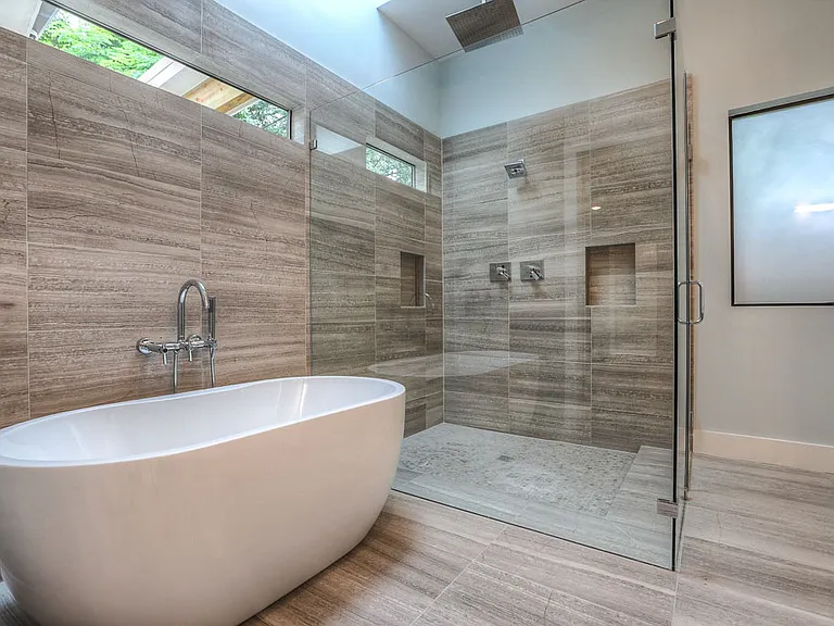 Master bath wide shot _ freestanding tub, rain-shower walk-in with bench seat, dual shower niches, and natural light from clerestory windows and skylight