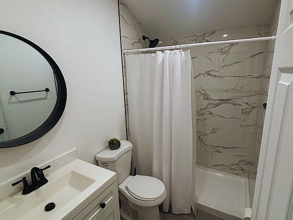 Impeccable bathroom with shower, toilet, mirror, towel set, and towel racks.