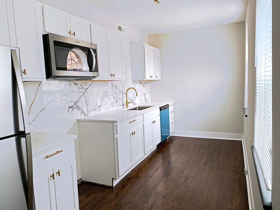 Galley kitchen with quartz countertops and stainless appliances (stovetop has been installed.) Three windows in kitchen.