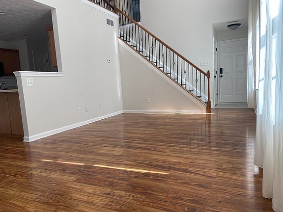 Living room looking at stairs to second level and foyer with closet