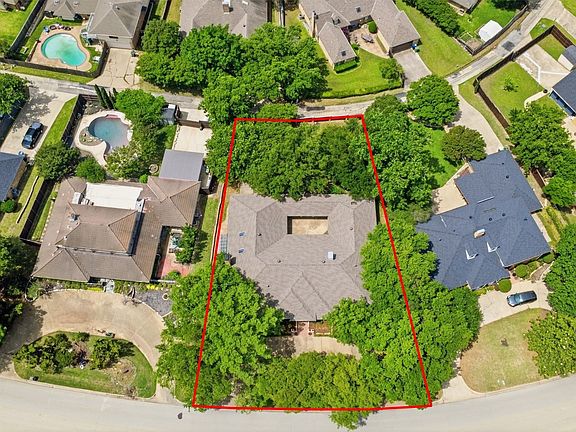 Expansive property with mature trees, featuring a central residence with a brown shingle roof and an internal courtyard