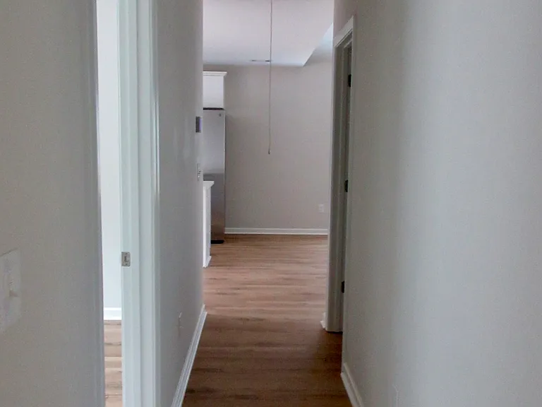 Hall leaving primary bedroom leading to kitchen