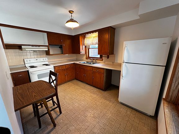 The kitchen has plenty of cabinet space, electric stove, refrigerator/freezer. Window over sink looking out to large grassy back yard defined by wooden and stone fencing