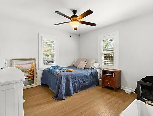 Secondary bedroom with furniture (archival photo) with two windows with plantain shutters, hardwood floors, ceiling fan and closet