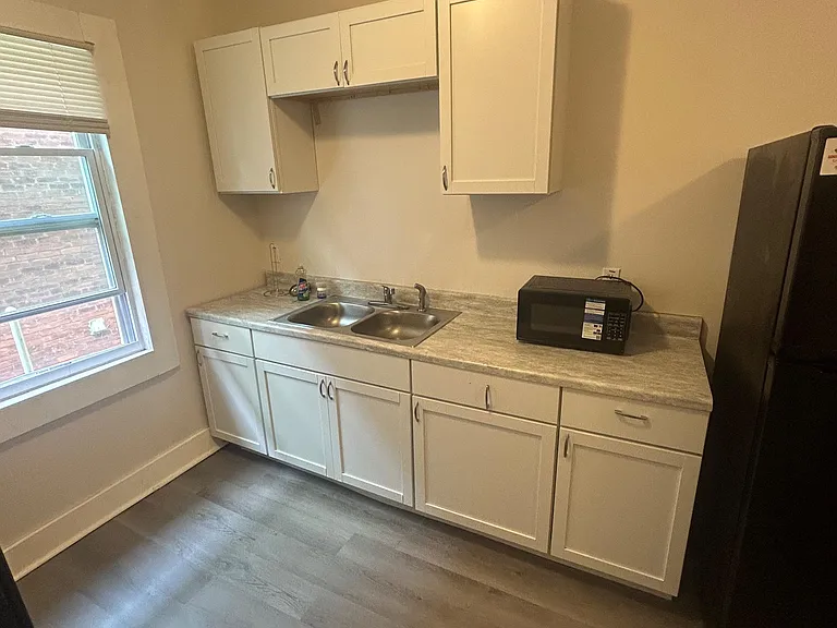 Efficient kitchen with generous white cabinetry, double-basin sink, ample counters, and a window for daylight.