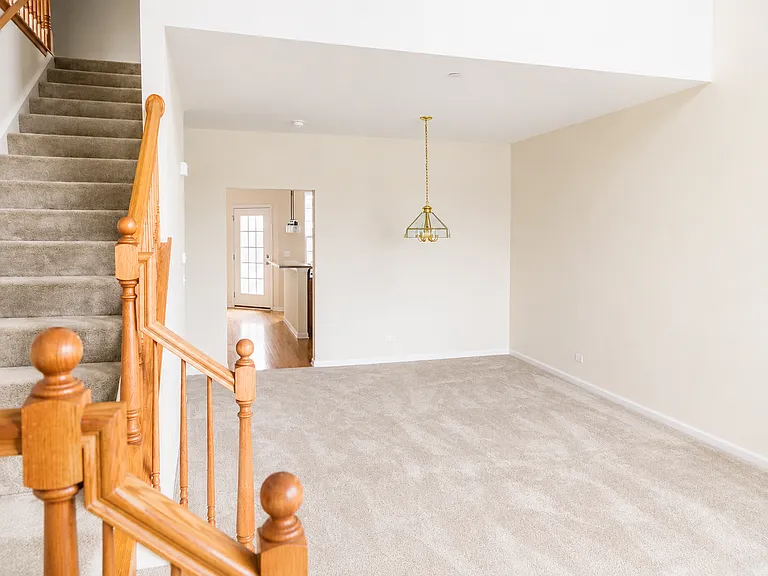 View from the front entrance into the living room and dining area, with the kitchen and patio door beyond.