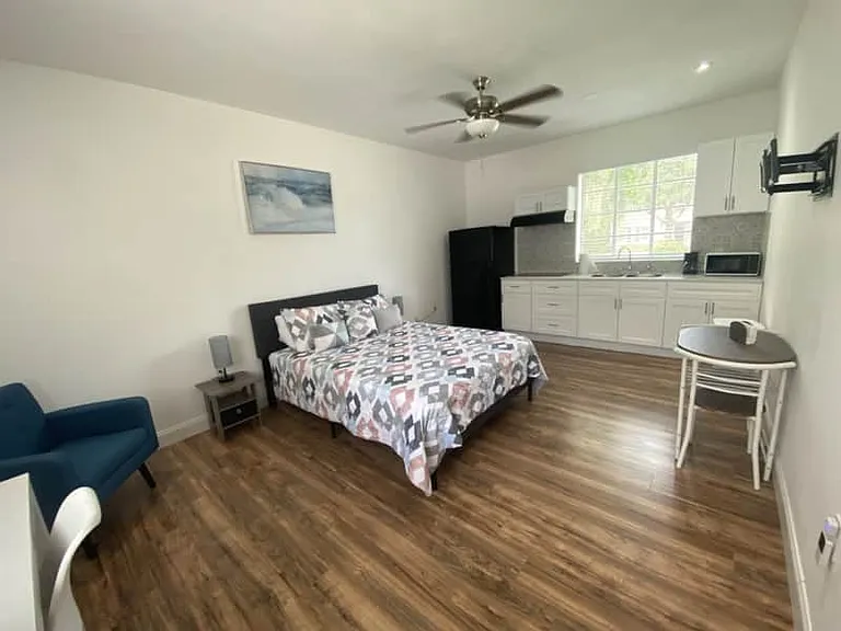 Room with nightstand, lamp, decor, cozy dining for two, and ceiling fan.