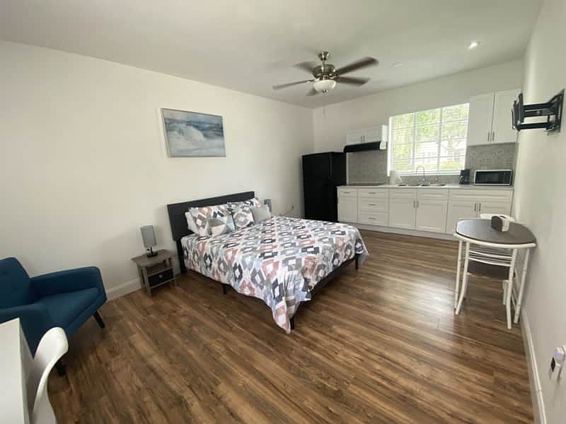 Room with nightstand, lamp, decor, cozy dining for two, and ceiling fan.
