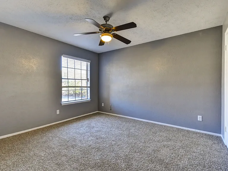 Generously sized bedroom with neutral tones and easy access to closets and bathroom.