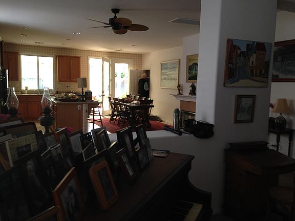 View from entry through to the great room: sitting area, kitchen and dining area. French door at rear leads to covered patio. Gas fireplace at the right with tile hearth.
