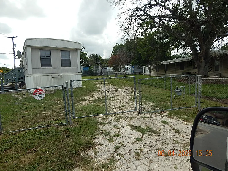 Entrance gate from Michelle Way showing front of home and stone driveway into yard - this on the north side of home