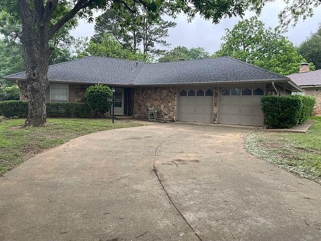 Ranch-style home featuring concrete driveway, an attached garage, and a shingled roof