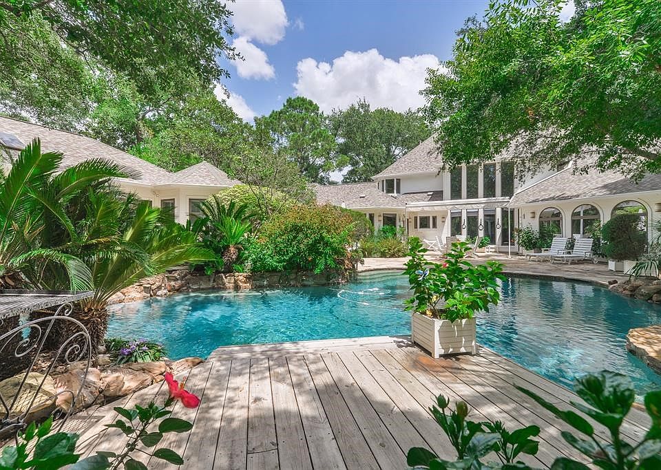 The lush landscaping sets off this view of the pool and home.