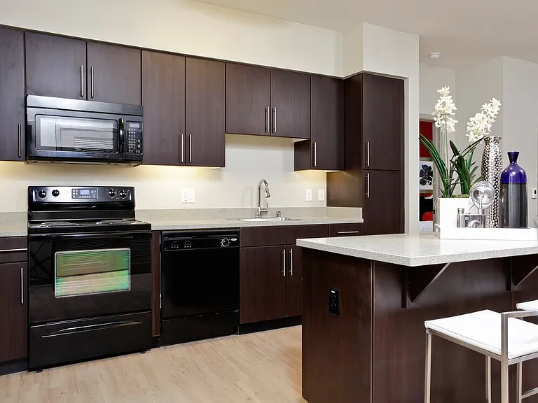 Classic Package I kitchen with black appliances, grey speckled granite countertops, espresso cabinetry, and hard surface flooring