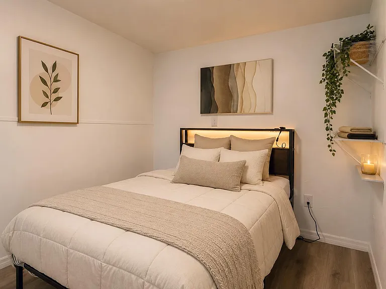 Furnished bedroom with a full-size bed, accent artwork, and convenient wall shelving for linens and essentials.