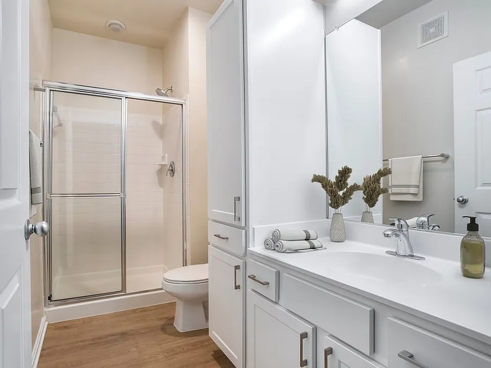 Renovated Package II bath with white countertops, white cabinetry, and hard surface flooring