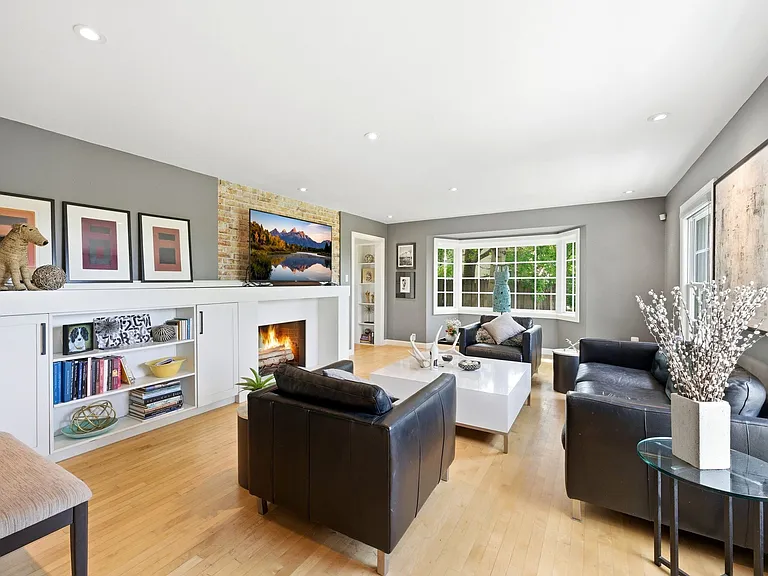 Main living room with tons of windows, built in shelving, and cozy fireplace.