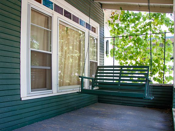 Front porch swing with grape vines behind it