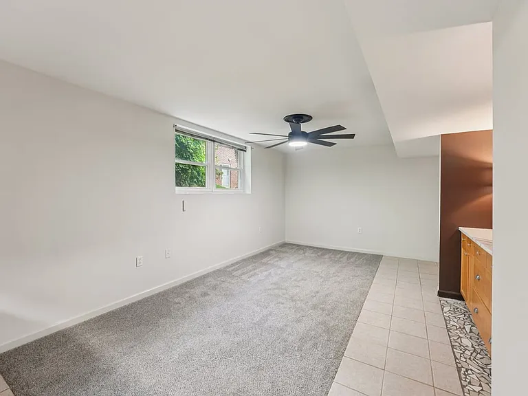 A bright lower level retreat with generous natural light, soft carpeting, and a convenient kitchenette, creating a flexible space that feels both practical and quietly enchanted.