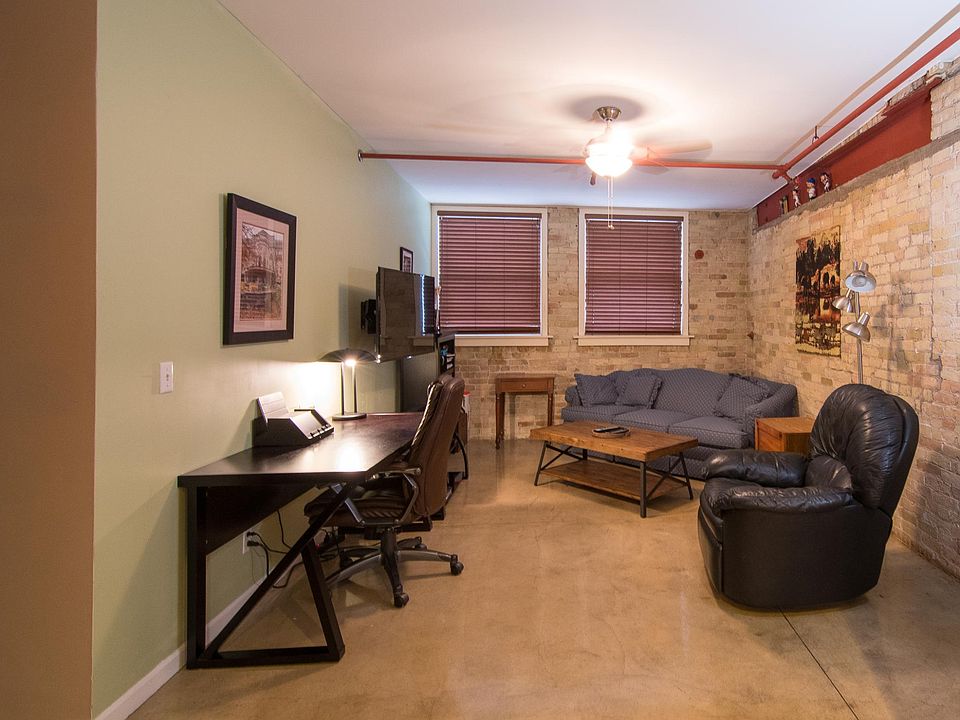 Big living room with two exposed cream city brick walls.