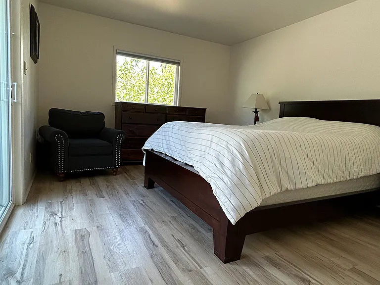Primary bedroom has a window to backyard, and a sliding glass door to the deck.