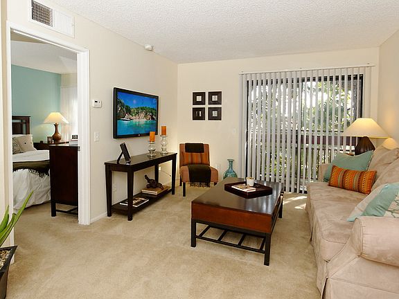 Staged living room with carpet and a sliding door leading to the balcony.