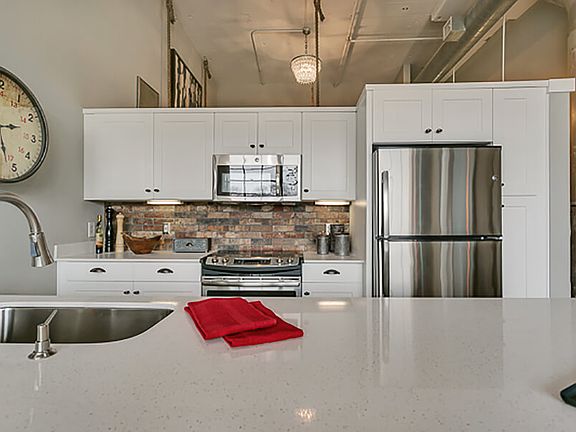 Modern kitchen with white cabinets and brick style backsplash, with white quartz countertop