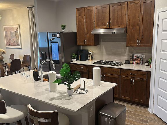 Eat-in kitchen with a large island, bar seating, ample wood cabinetry, and stainless appliances, plus adjacent dining area.