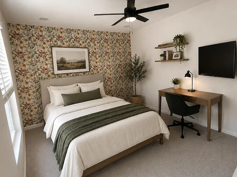 Furnished bedroom with a queen bed, accent wall, ceiling fan, wall-mounted TV, and a dedicated desk workspace.