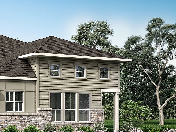 A two-story residential house with a gabled roof, surrounded by lush greenery and a clear blue sky i